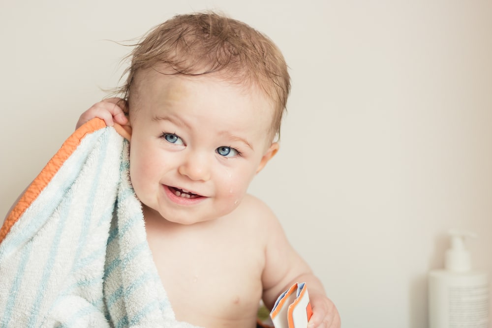 En søt baby som tørker øret sitt. Det er ikke alltid like enkelt å få vann ut av øret.