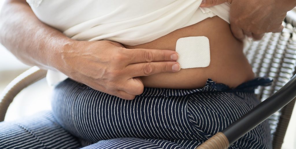 Bilde av dame som sitter og har tatt på østrogenplaster.
