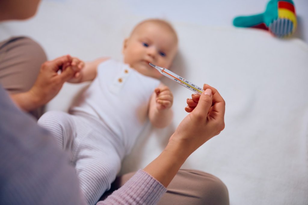 Close up of mother measuring baby's temperature at home.