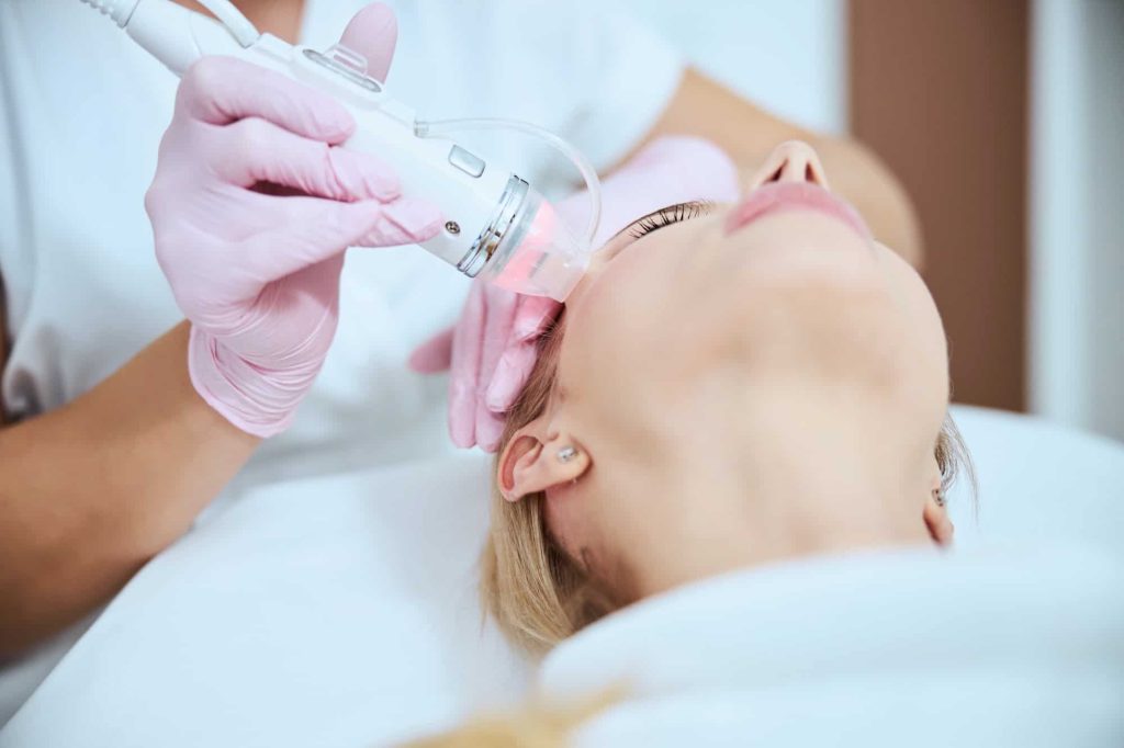 Cosmetologist treating her patient with a microneedle beauty machine