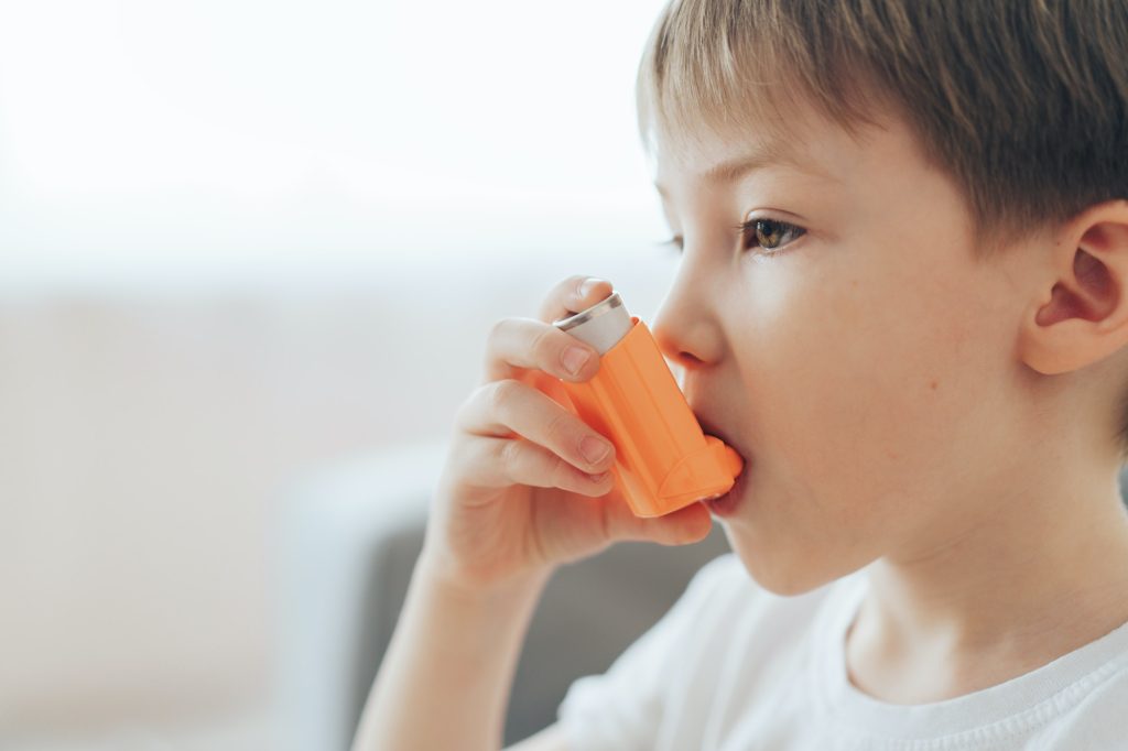 En liten gutt inhalerer medisin gjennom en astmainhalator