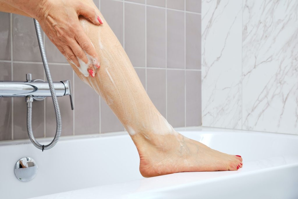 Eldre kvinne som vasker føttene på badet