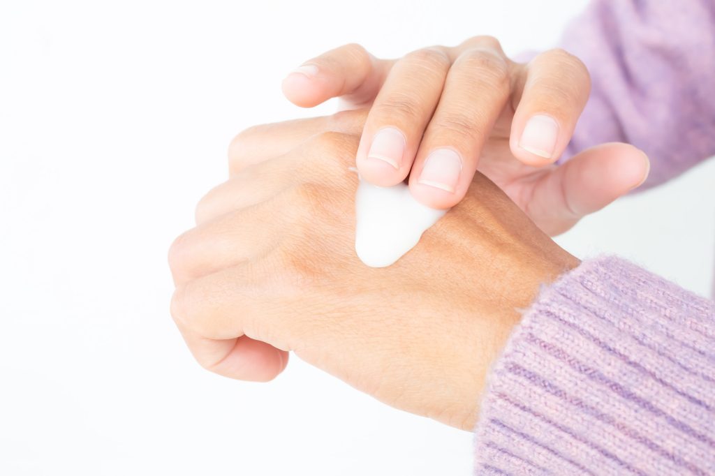 En dame som tar på seg lotion. Laser etterbehandling. 
