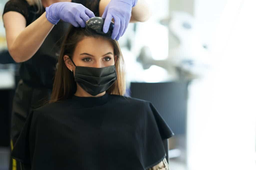 Adult woman at hairdresser wearing protective mask due to coronavirus pandemic