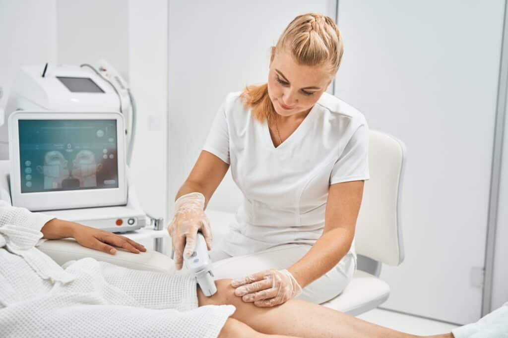 Cheerful cosmetologist holding gadget for laser epilation