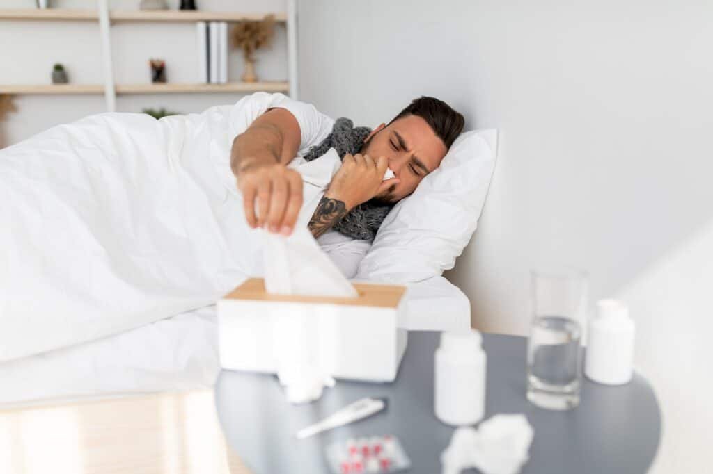 Cold, flue, coronavirus concept. Sick guy taking napkins from tissue box and sneezing runny nose