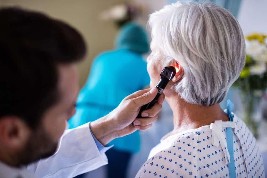 Doctor examining patients ear with otoscope
