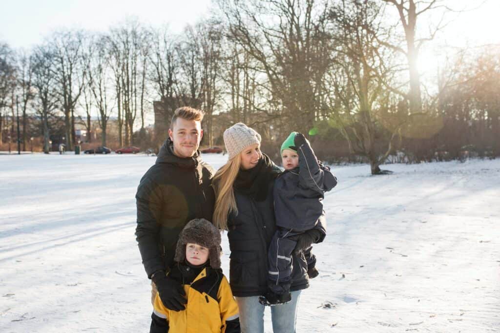 Portrait of young man with family standing on snow covered field