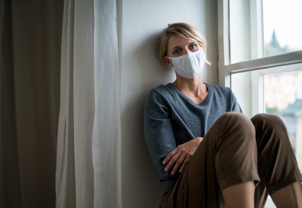 Woman indoors at home feeling stressed, mental health and coronavirus concept.