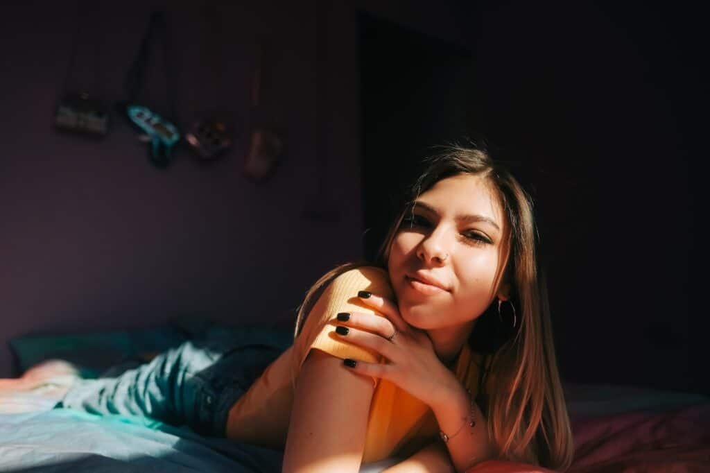 Young attractive caucasian woman relaxing on a bed in sunlight.
