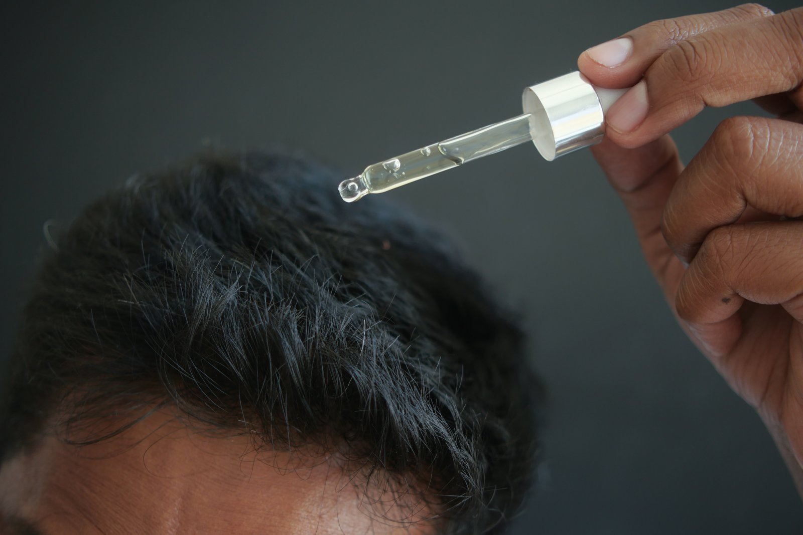 young men applying essential oils on his hair