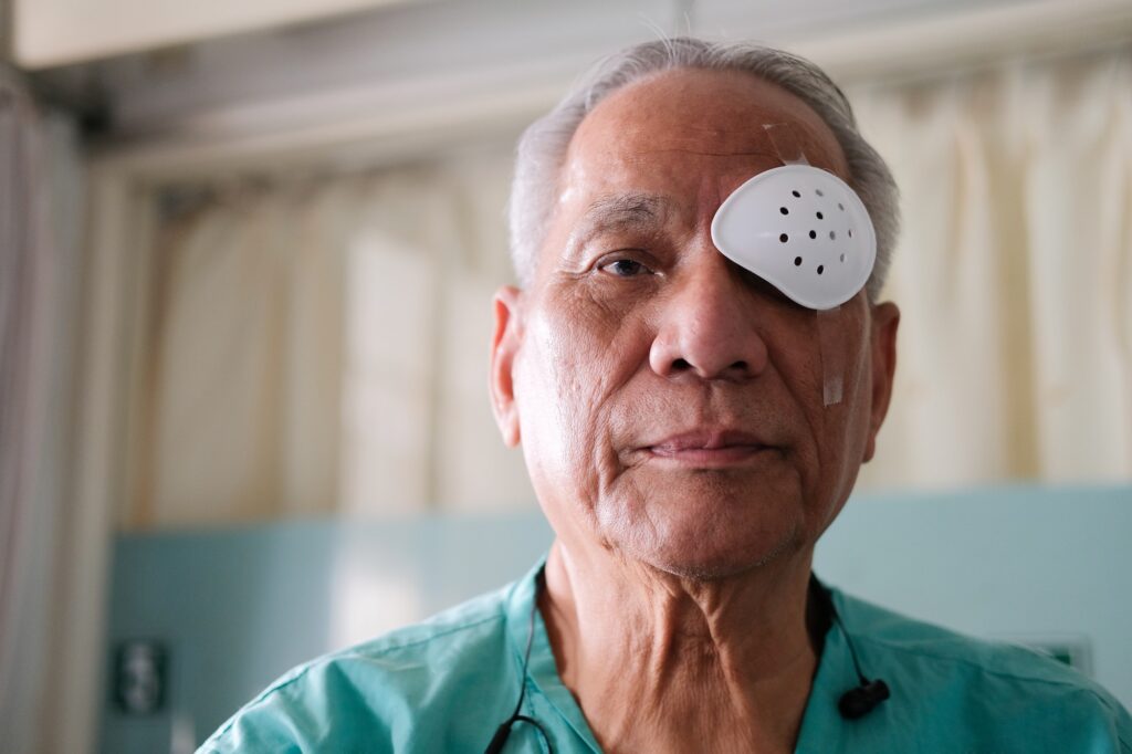 patient covering eye with protective shield & medical plaster after eyes cataract surgery in