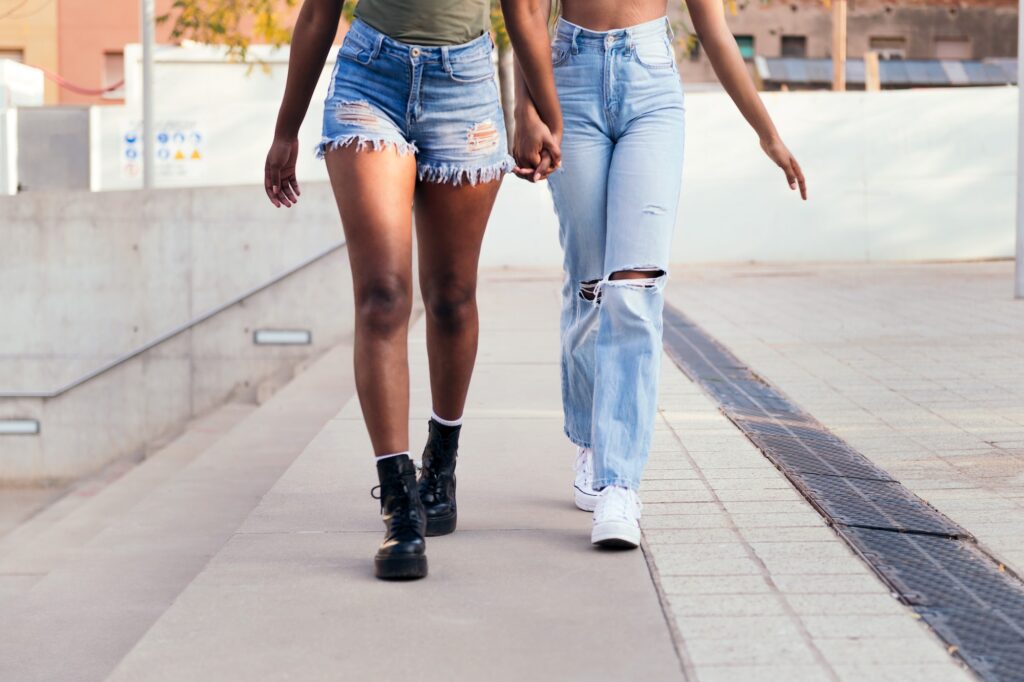 legs of two young women strolling holding hands