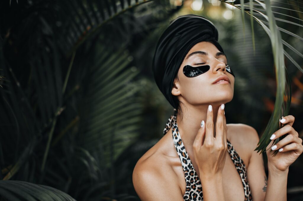 Magnificent woman with eye patches touching chin. European girl in black turban posing on exotic ba