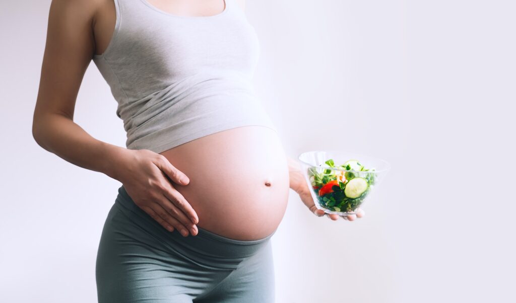 Pregnant woman eating healthy food containing folic acid, B9 vitamin.