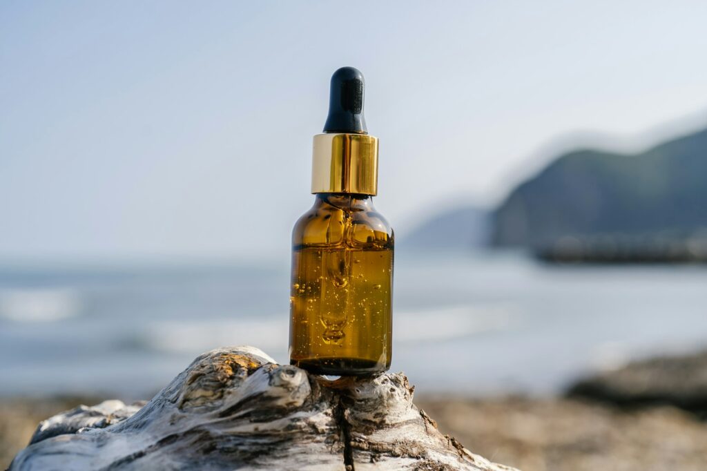 A bottle of serum on stones on a sea background.