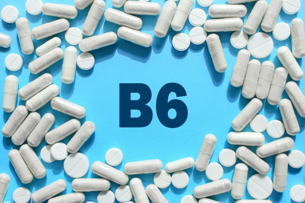 Vitamin B6 text in white capsules frame on blue background. Pill with Pyridoxine; Pyridoxal. Dietary