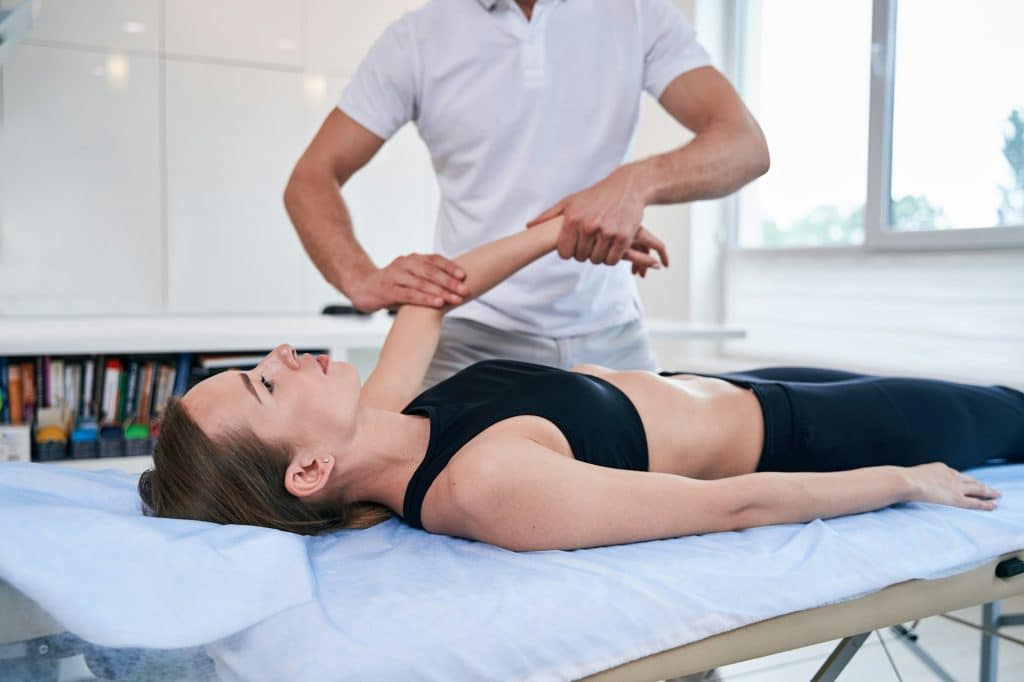 Nice young female getting professional treatment with pain in hand in wellness center