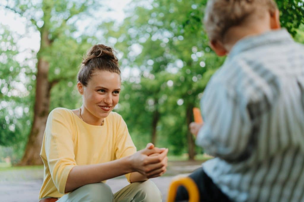 Mother feeding her son with healty snack in a park.