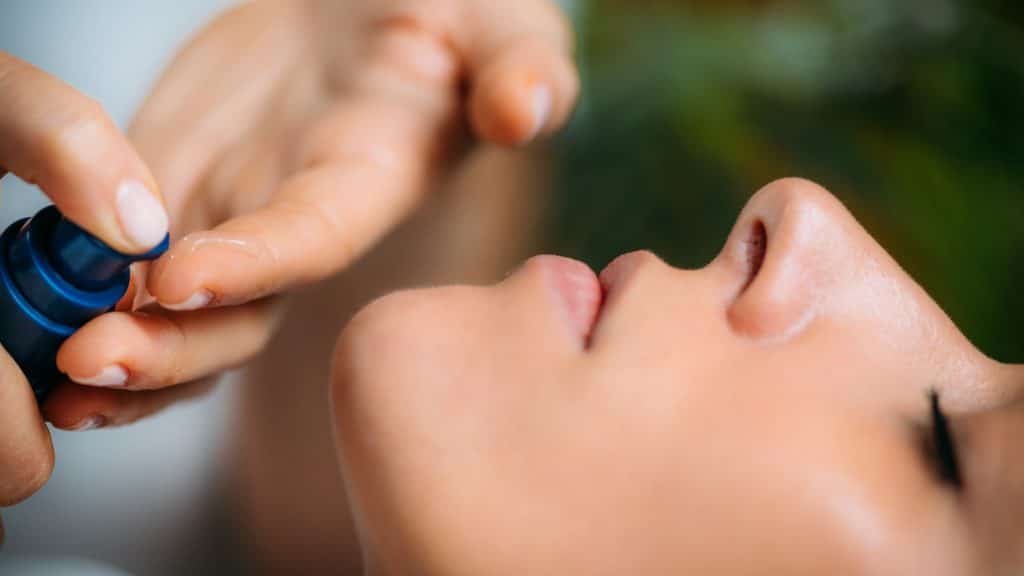 Retinol Treatment. Cosmetician Applying Retinol Serum on Woman’s Face