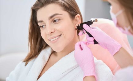 Woman is putting an ear piercing machine to her ear